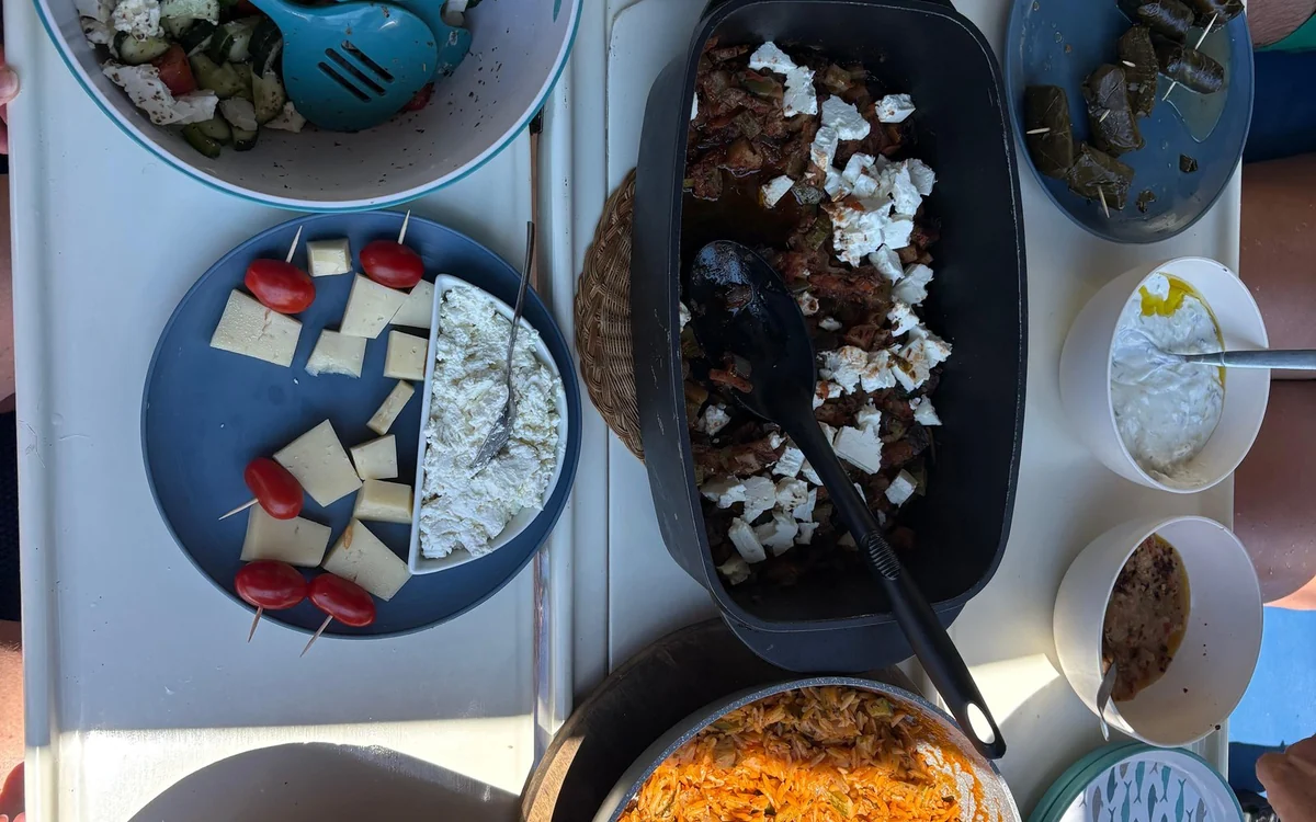 Greek salad, cheese and a tray of meat with feta on a table on deck