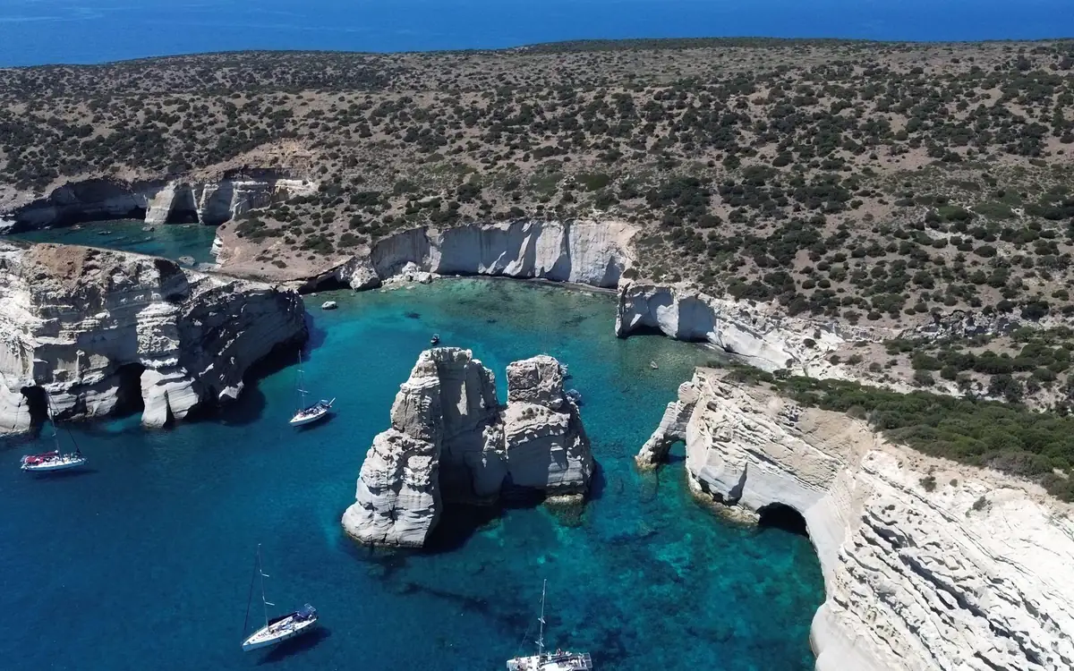 Formaciones de roca blanca en una bahía turquesa con veleros amarrados alrededor, vistas desde arriba