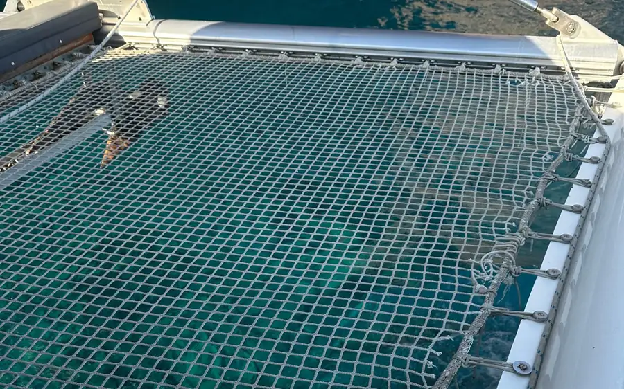 Das Netztrampolin eines Katamarans über grünblauem Wasser